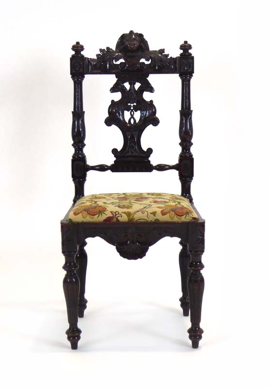 A 19th century figural carved oak side chair with a drop-in seat over a shaped apron on turned legs