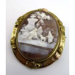 A late 19th century yellow metal mounted cameo brooch of oval form depicting figures by a fountain