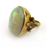 An 18ct yellow gold ring set oval cabochon opal within a diamond set fleur de lis mount,