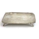 A 19th century Dutch metalware tray of square form with leaf design corners on four outswept feet,