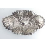 An early 20th century metalware dish of oval form repousse decorated with flowerheads on four