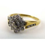 A 9ct yellow gold cluster ring set small diamonds, the shoulders each set three further diamonds,