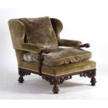 A late 19th/early 20th century low open armchair with a walnut frame and green upholstery,