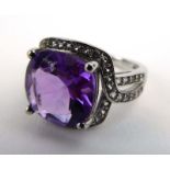 A silver dress ring set cushion cut amethyst within a border of lab white sapphires,
