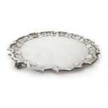 A small Edwardian silver salver of circular form with piecrust border on three scrolled feet,