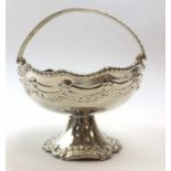 A small metalware dish, the swing handle above a body decorated in the Rococo manner, d.