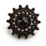 A 19th century yellow metal brooch of tiered flowerhead form set garnets and small pearls, d. 3.
