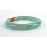 A pale green/brown jade bangle, internal d. 6.