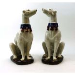 A pair of majolica stoneware figures, each modelled as a seated hound wearing a tasselled collar, h.