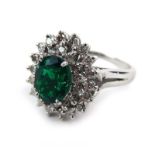 A 14ct white gold cluster ring set oval cut Zambian emerald within a border of small diamonds,