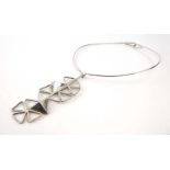 A metalware torque necklace suspending a silver pendant of triangular flowerhead form, Norman Grant,