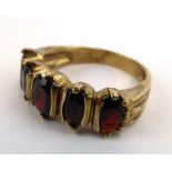 A 9ct yellow gold ring set five graduated oval garnets in a wide setting, ring size O, 4.