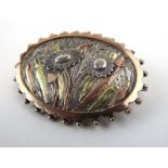 A late 19th/early 20th century silver and gold overlaid brooch of oval form relief decorated with