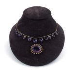 An Edwardian 9ct yellow gold fringe necklace suspending thirteen graduated oval drops set purple