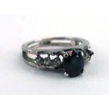 An 18ct white gold ring set oval dark green/blue stone in a raised four claw setting,