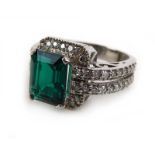 A 14ct white gold ring set emerald cut Zambian emerald within a border of small diamonds,