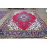 A 20th century Tabriz carpet, the red ground with a central medallion within matching bands,