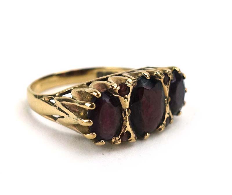 A 9ct yellow gold ring set three graduated garnets interspersed with four smaller garnets in a