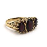A 9ct yellow gold ring set three graduated garnets interspersed with four smaller garnets in a