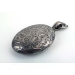 An early 20th century florally engraved metalware locket of oval form, l.