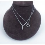 A 9ct white gold fine flat curblink necklace suspending an openwork pendant of heart shaped form