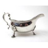 A silver gravy boat of typical form with gadrooned border, c-scroll handle and hoof feet,