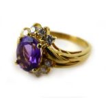 An 18ct yellow gold ring set oval amethyst and ten small diamonds in a crossover setting,