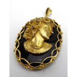 A black onyx pendant of oval form mounted in 9ct yellow gold and depicting a female beauty wearing