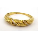 An 18ct yellow gold hinged bracelet set three rows of small brilliant cut diamonds within a