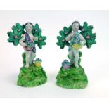 A pair of Staffordshire bocage figures each modelled as a flower gatherer on a naturalistic base,