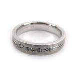 An 18ct white gold band ring set seven small diamonds within recessed settings on a matt shank,