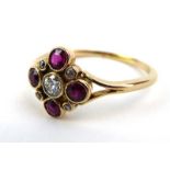 An early 20th century yellow metal ring set four rubies and five diamonds in openwork rubover