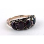 An early 20th century 9ct yellow gold ring set five graduated oval cut purple glass sections,