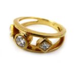 A yellow metal ring of openwork design set one brilliant and two princess cut diamonds in rubover