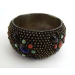 An Eastern cuff bracelet inset semi-precious stones including lapis lazuli, turquoise and others,