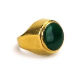 A Chinese yellow metal ring set cabochon jadeite in a raised rubover setting, stamped '22',