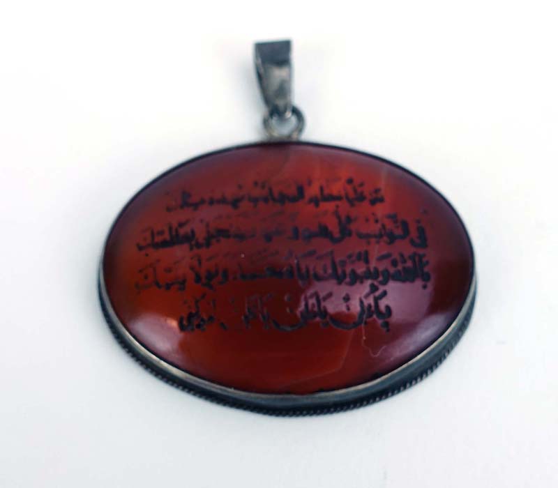 A metalware mounted cornelian pendant of oval form carved with Islamic text, w.