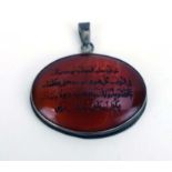 A metalware mounted cornelian pendant of oval form carved with Islamic text, w.