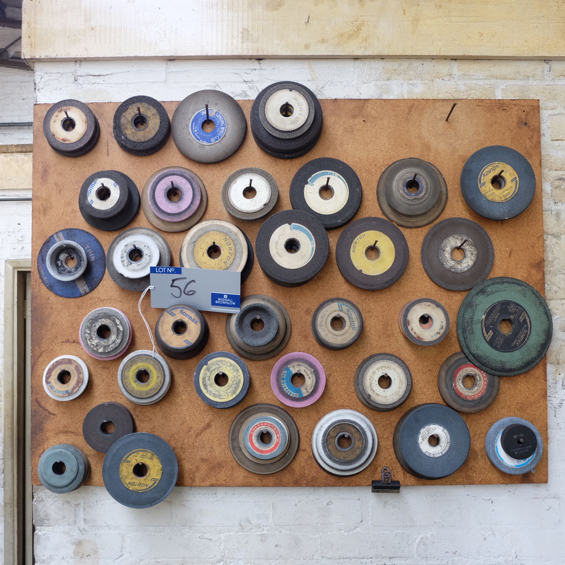 Assorted Used Grinding Wheels on wall rack and bench.