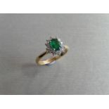 0.80ct emerald and diamond cluster ring set with a oval cut (treated) emerald which is surrounded by