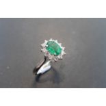 0.80ct emerald and diamond cluster ring set with a oval cut( treated) emerald which is surrounded by