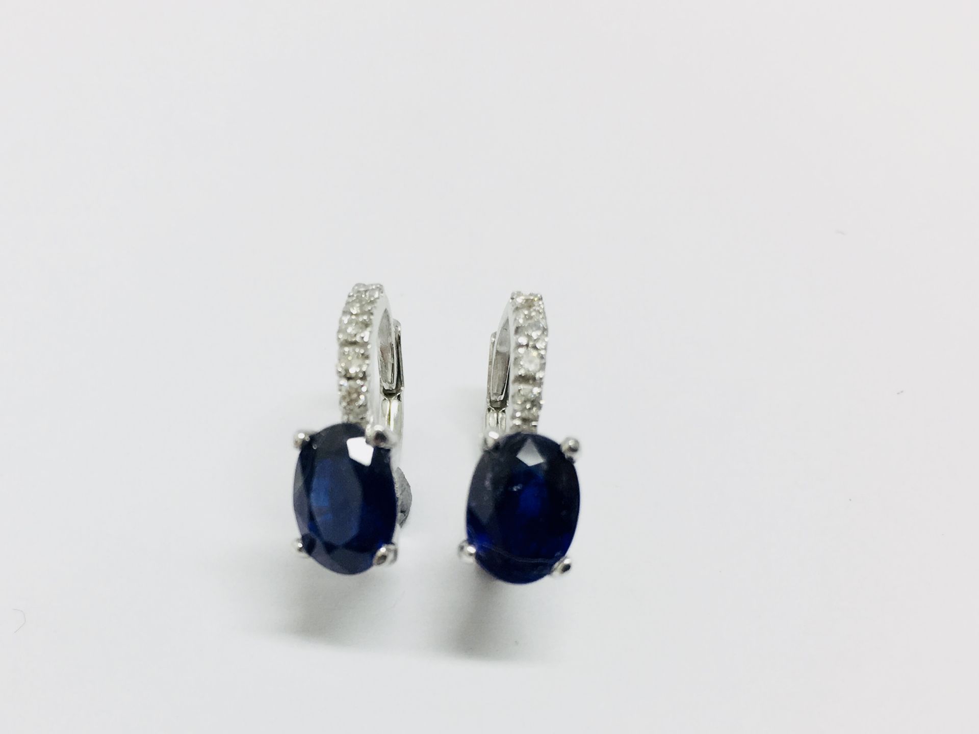 1.60ct sapphire and diamond hoop style earrings. Each is set with a 7x 5mm oval cut sapphire (