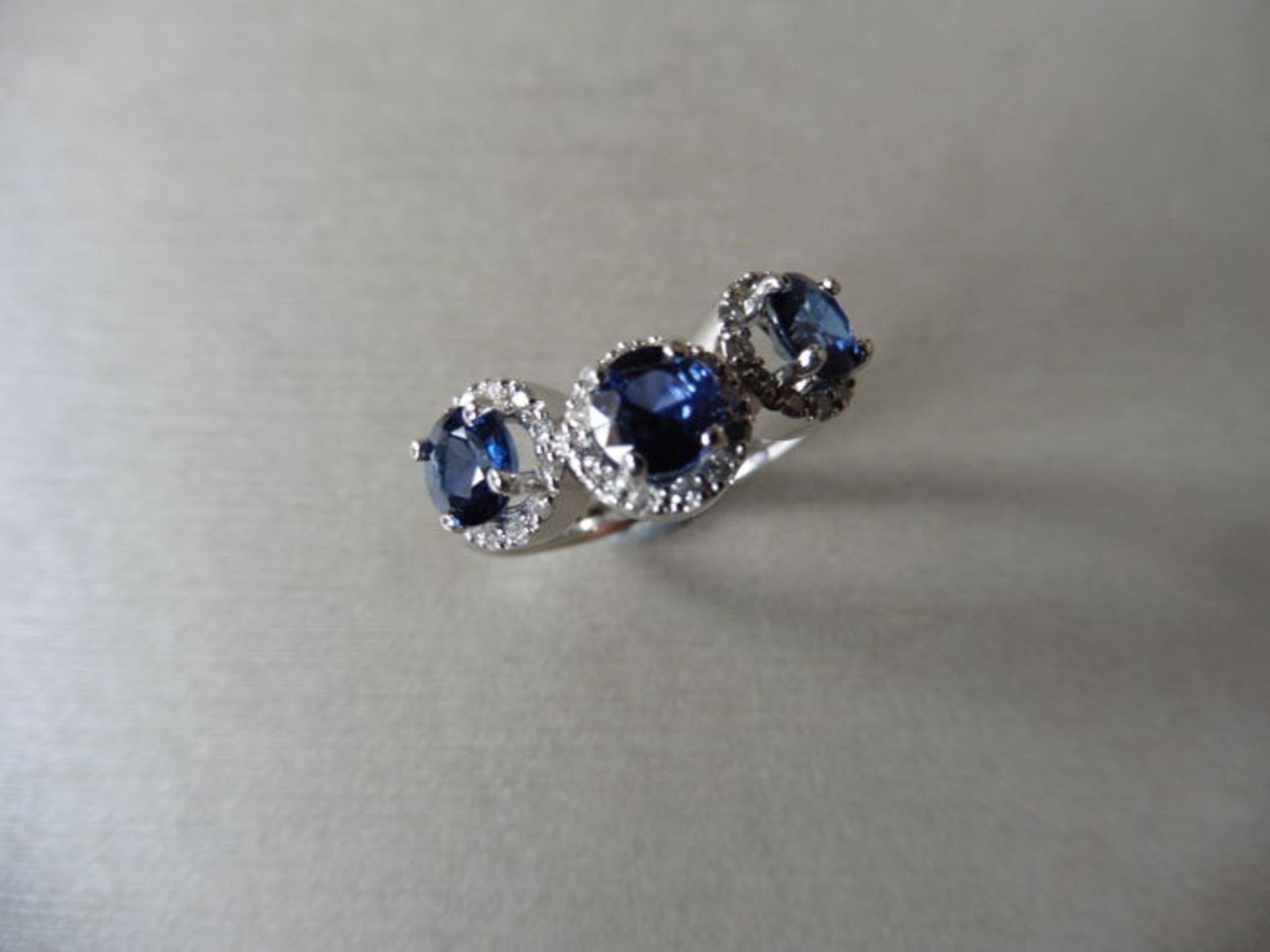 18ct white gold trilogy ring set with 3 round cut sapphires weighing 0.70ct. These are surrounded in