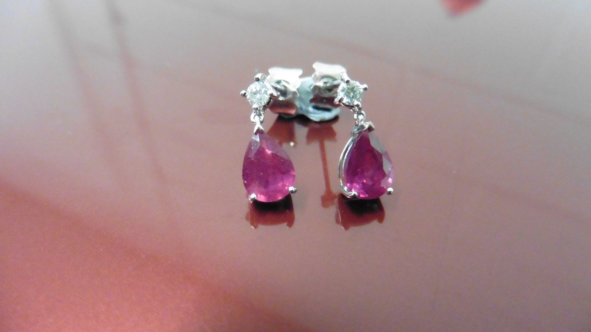 0.70ct drop style earrings. Each set with a pear shaped ruby ( glass filled ) and a small