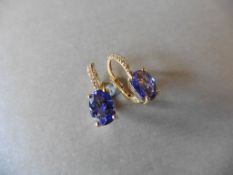 1.60ct Tanzanite and diamond hoop style earrings. Each is set with a 7x 5mm oval cut Tanzanite (