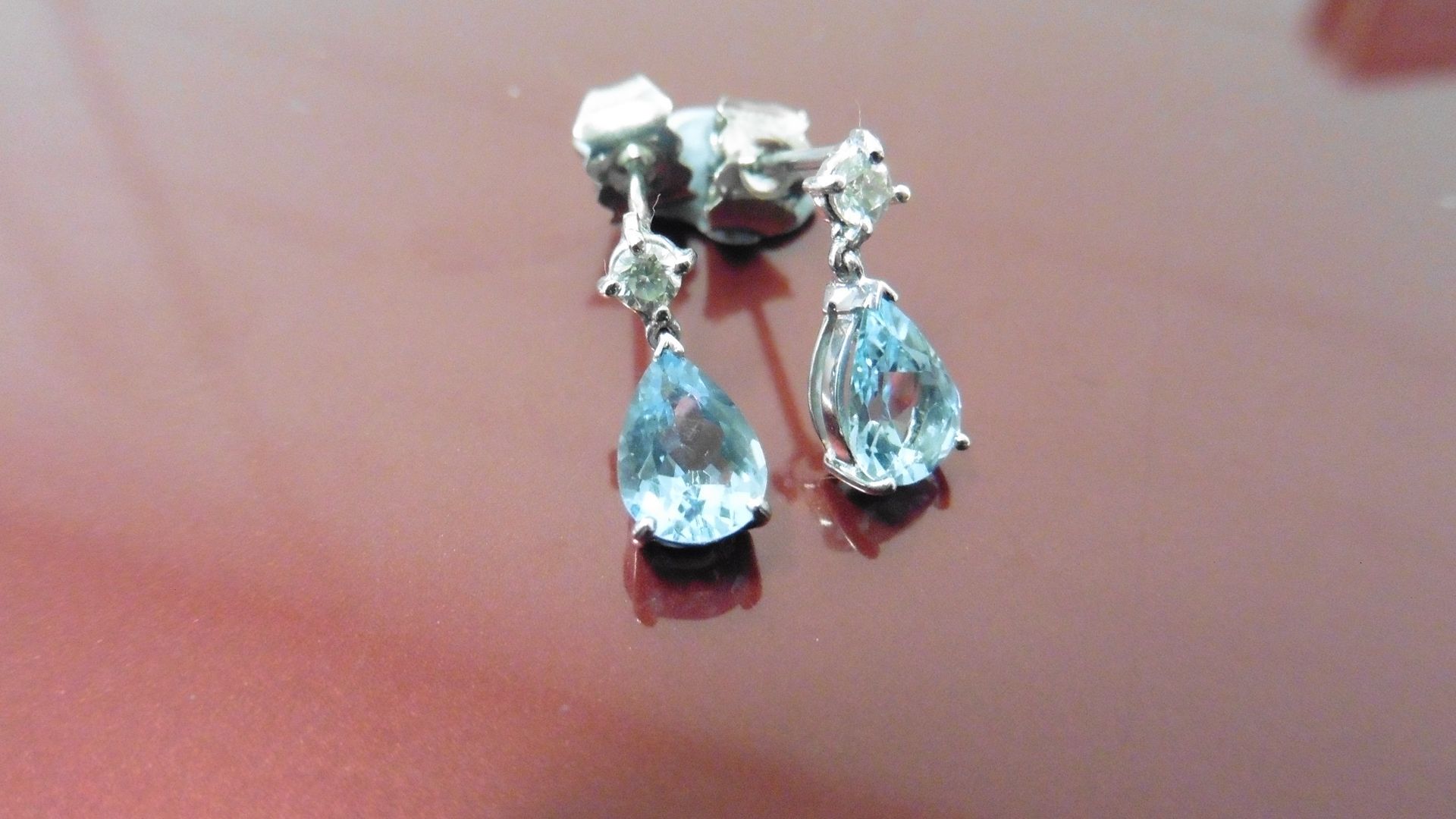 0.70ct drop style earrings. Each set with a pear shaped Aqua marine ( treated ) and a small