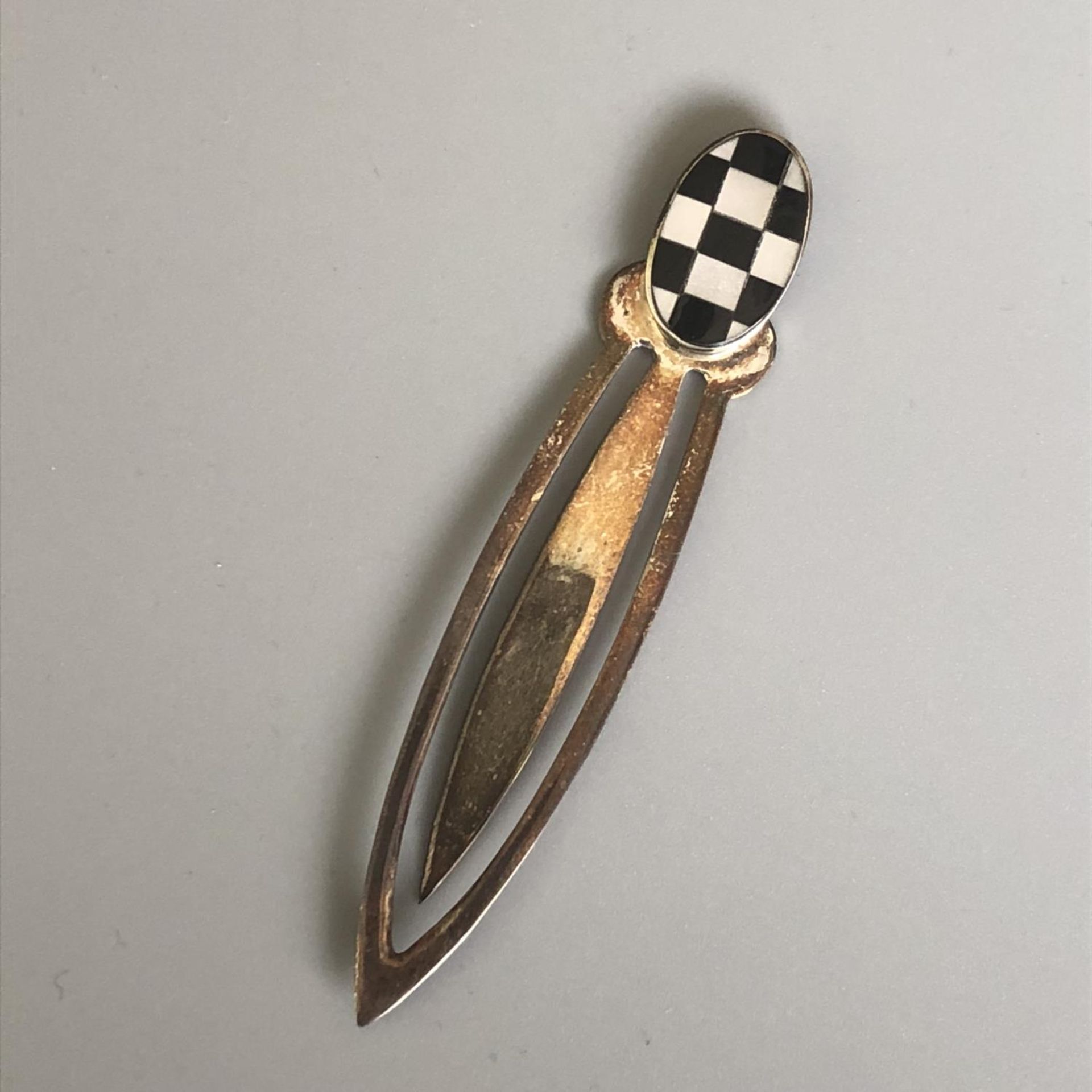 A hallmarked silver book mark or money clip with checkered black and white finial