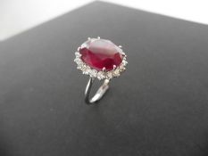 8.50ct ruby and diamond cluster dress ring set in platinum. Oval cut ruby ( fracture filled )