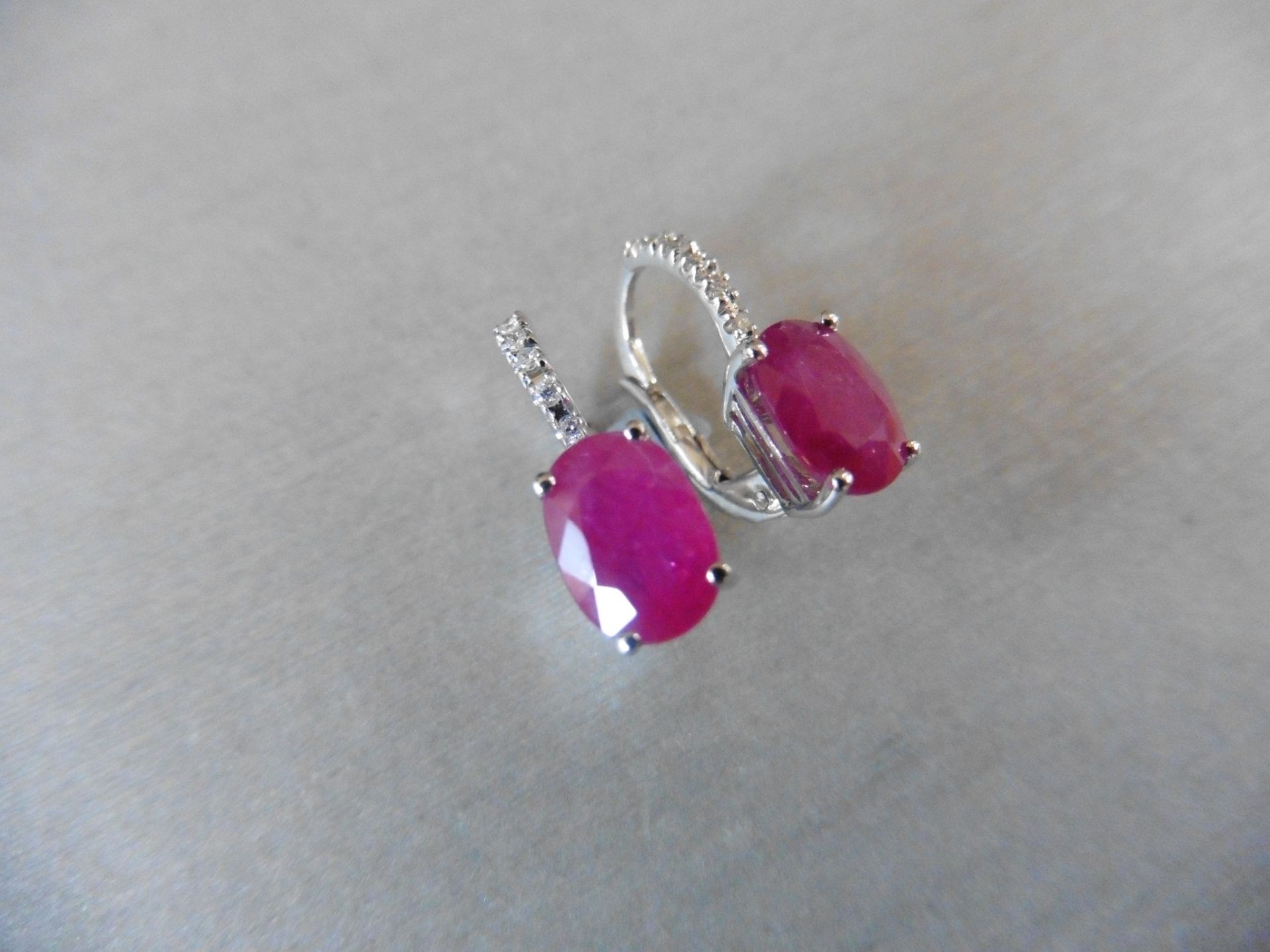 1.60ct Ruby and diamond hoop style earrings. Each is set with a 7x 5mm oval cut Ruby (treated)