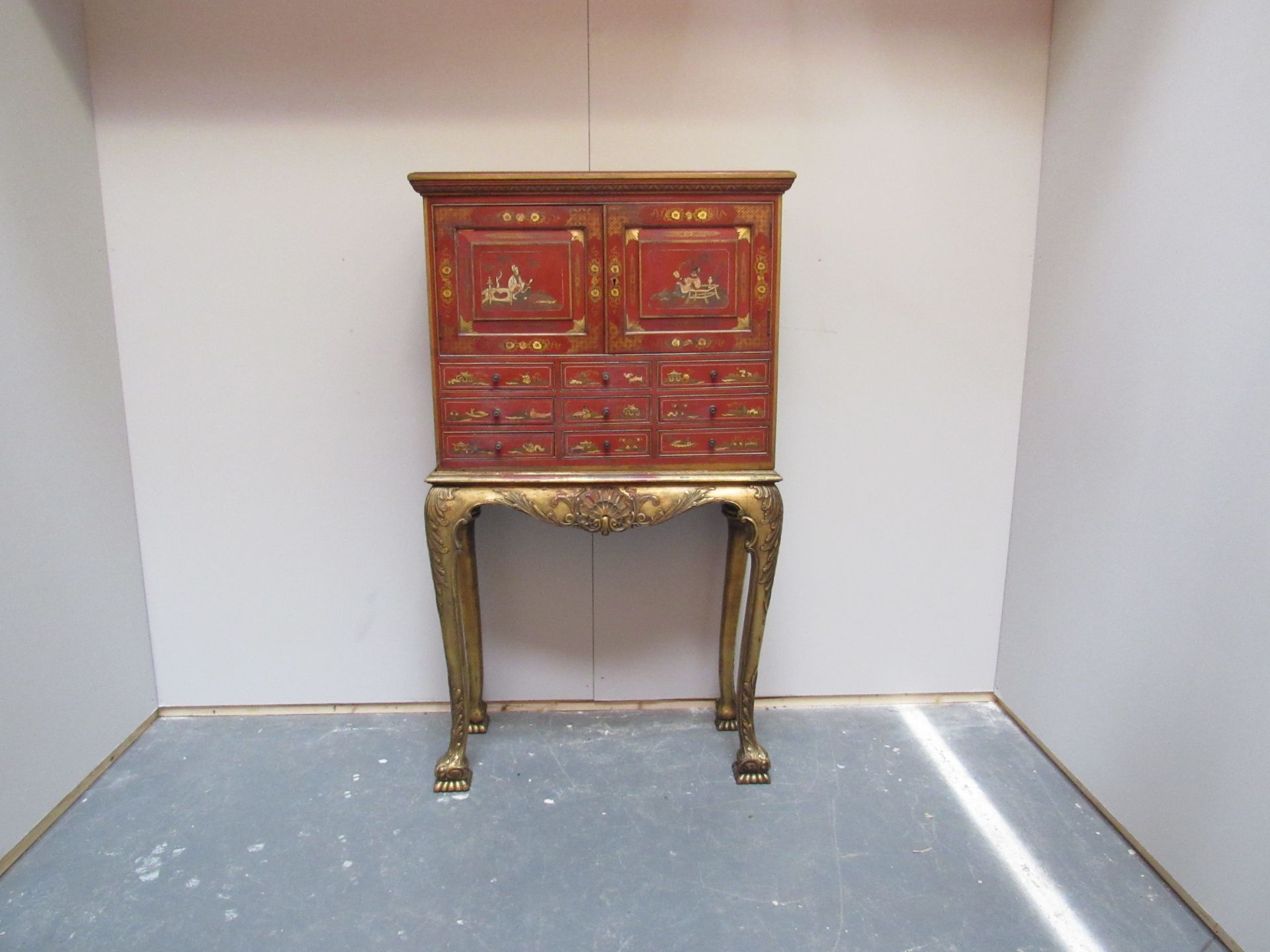 Red lacquered cabinet on a gilt stand raised on bold cabriole legs and bold carved club feet